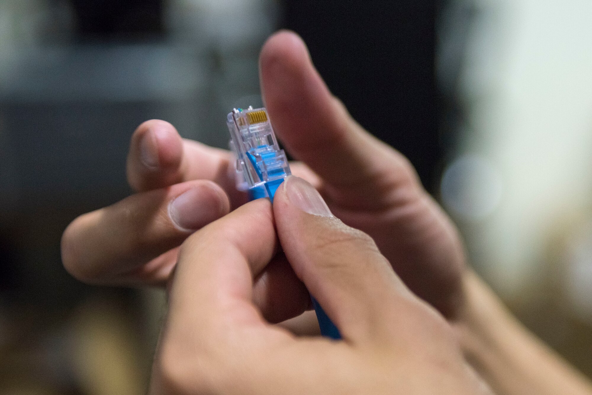 Airman 1st Class Andrews De Leon, 374th Communications Squadron Operations Flight client systems technician apprentice, attaches a clip to the end of an Ethernet cable at Yokota Air Base, Japan, April 4, 2018.