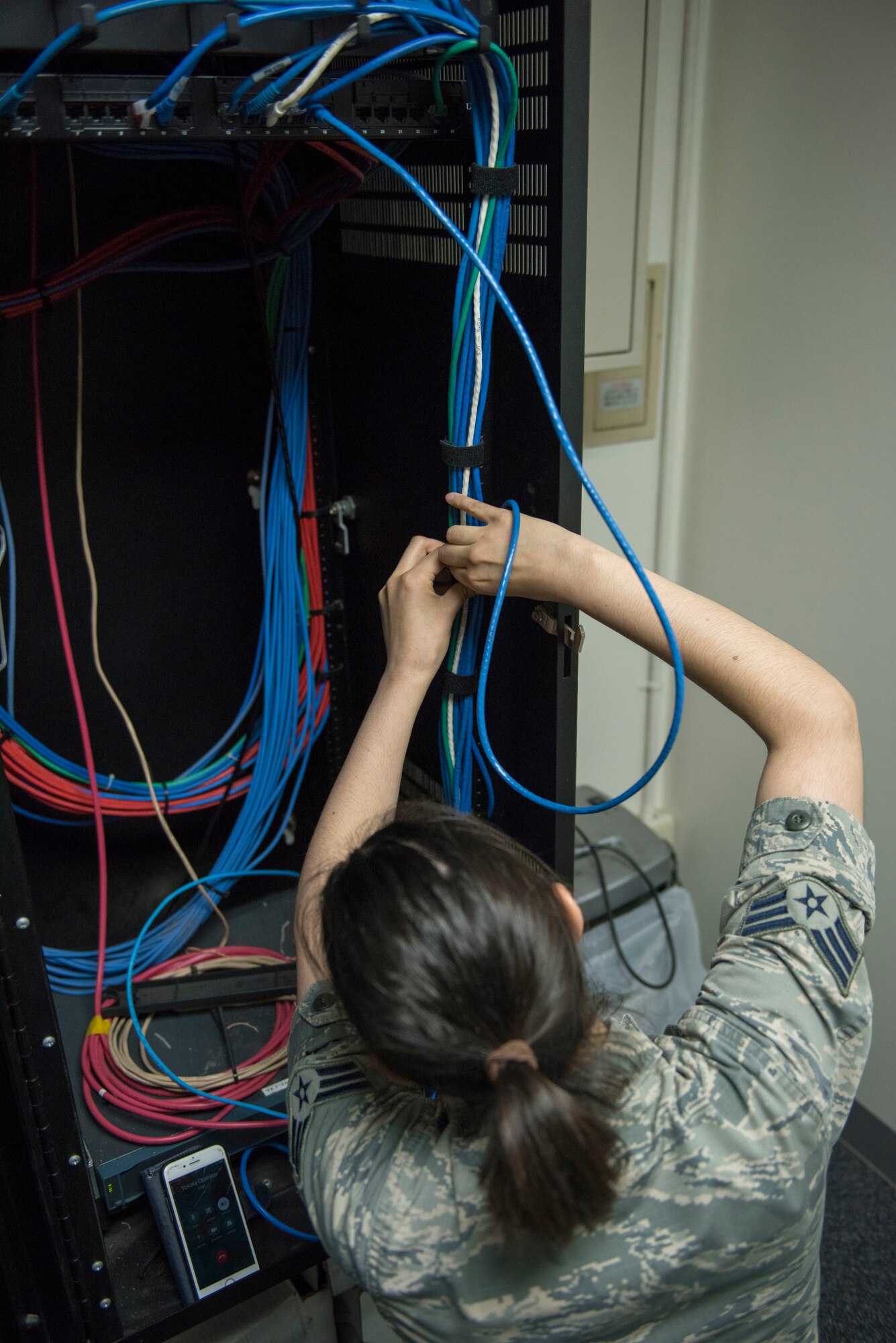Senior Airman Amy Kristoffersen, 374th Communications Squadron Operations Flight client systems technician journeyman, performs some cable management prior to completing a printer swap at Yokota Air Base, Japan, April 4, 2018.