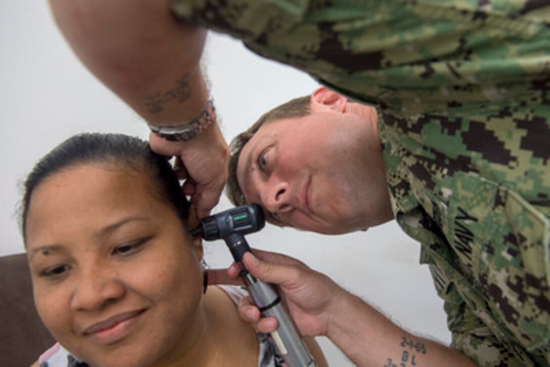 A military audiologist looks inside a patient's ear.