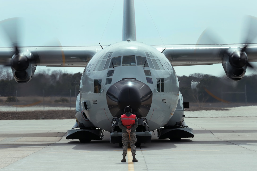 An airman guides a LC-130 Hercules aircraft.