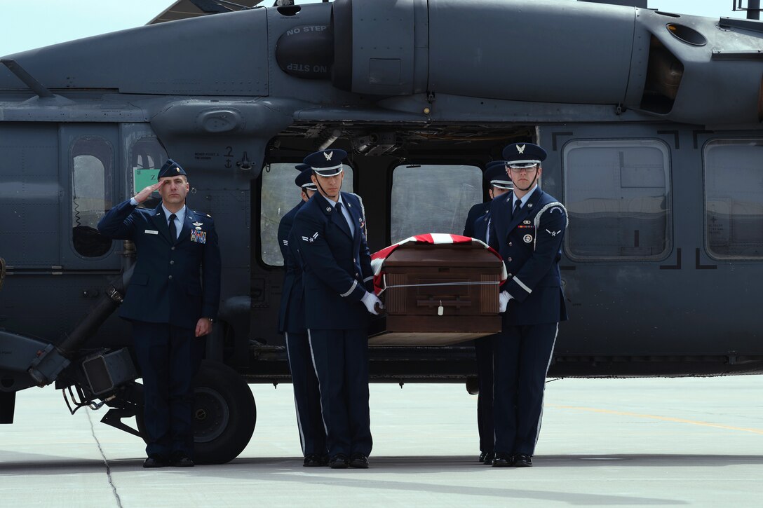 Airmen carry a flag-covered coffin from a helicopter.