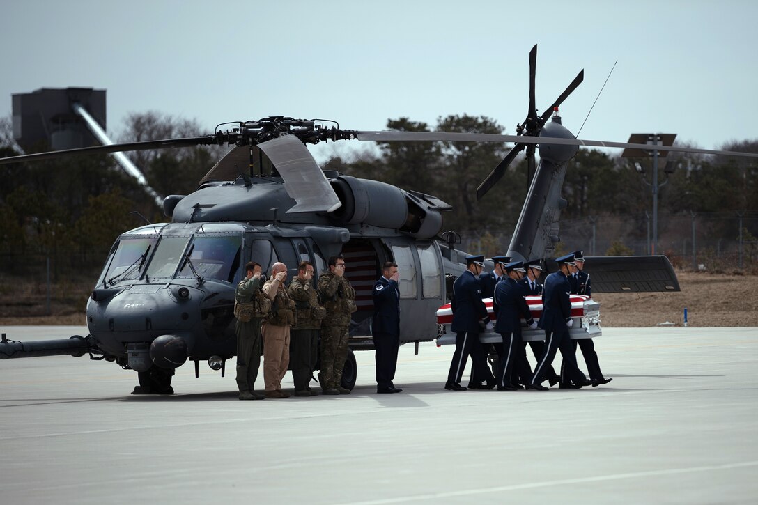 Airmen carry a flag covered coffin from a helicopter.