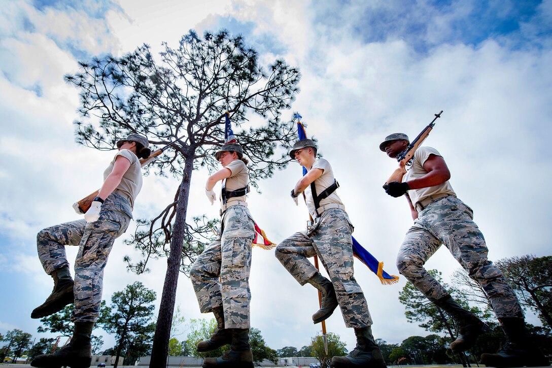 Four airmen march in a line outside.