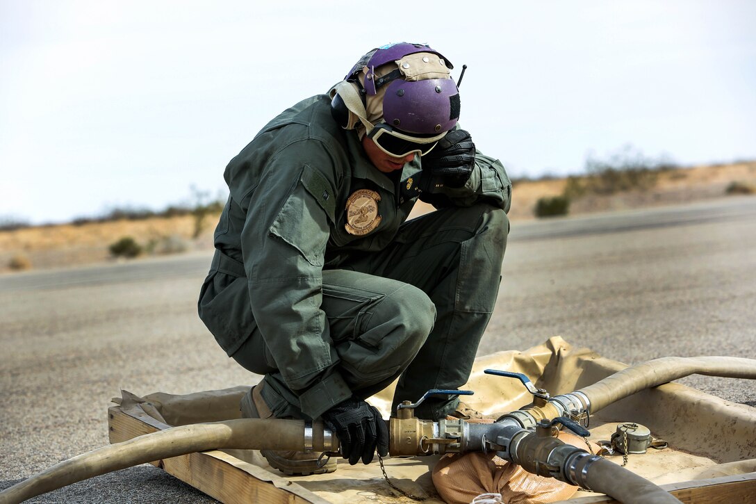 A Marine tightens a fuel hose clamp.