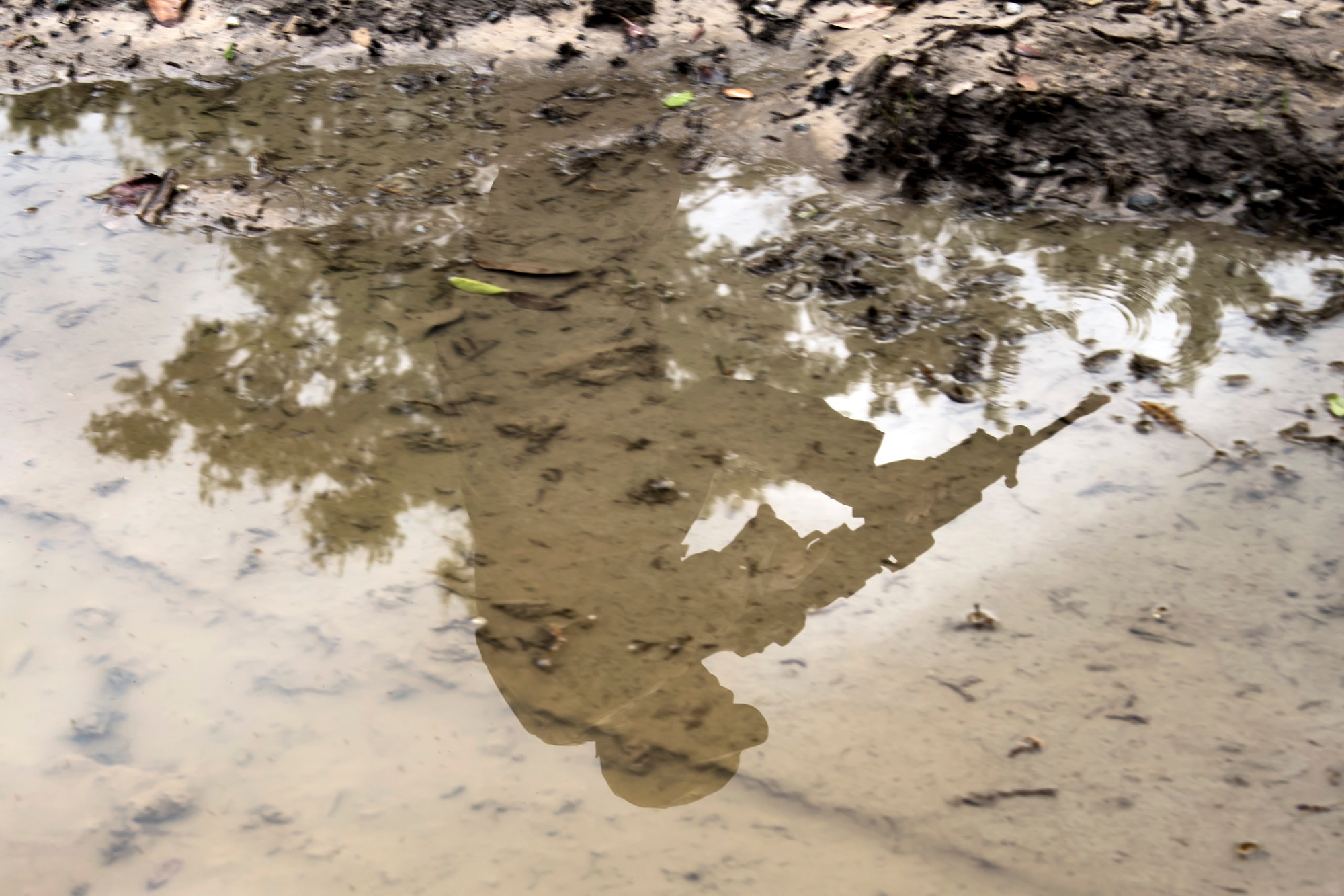 A puddle shows the reflection of an Airman from the 820th Base Defense Group (BDG) during a dismounted operations training, March 27, 2018, at Moody Air Force Base, Ga. The dismounted ops training is part of an Initial Qualification Training, which gives new Airmen coming into the BDG an opportunity to learn a baseline of basic combat skills that will be needed to successfully operate within a cohesive unit while in a deployed environment. (U.S. Air Force photo by Airman Eugene Oliver)