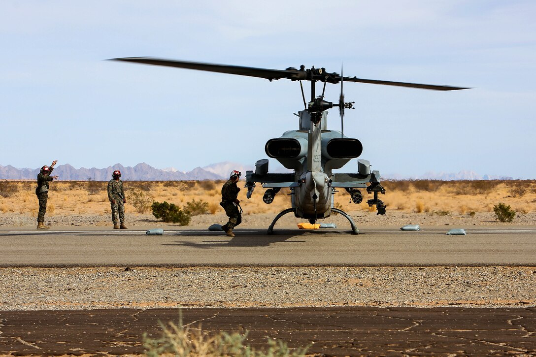Marines prepare an AH-1 Cobra helicopter for takeoff.