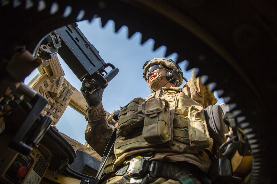 A soldier looks out away from a military vehicle.