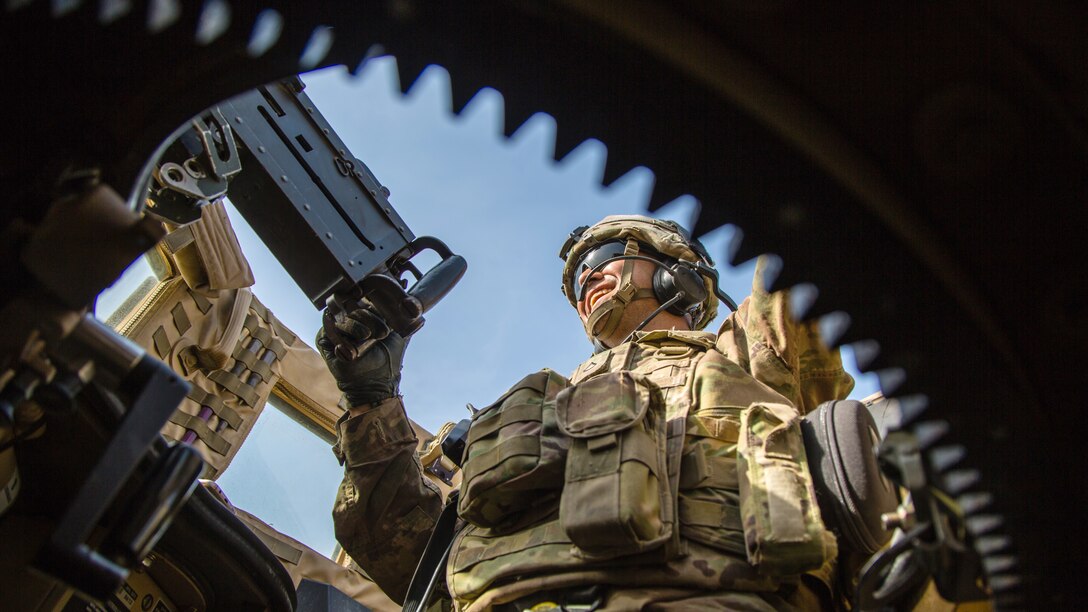 A soldier looks out away from a military vehicle.