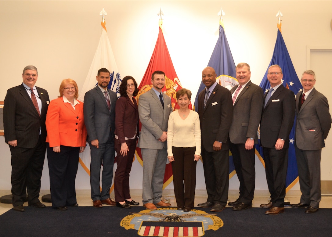 The Defense Acquisition University Senior Service College Fellowship Program participants pose with Hue Nguyen, center, DLA Troop Support flag room supervisor, at DLA Troop Support in Philadelphia April 3, 2018.