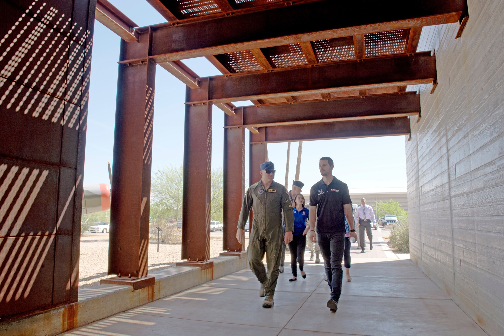 Lt. Col. Rhett Hierlmeier, 61st Fighter Squadron commander; and Alexander Rossi, Andretti Autosport racecar driver, walk through the entrance to the 61st FS operations building at Luke Air Force Base, Ariz., April 5, 2018. Rossi and other delegates from Andretti Autosport learned about the lives and work of pilots, maintainers and other Airmen who support the mission to build the future of airpower. (U.S. Air Force photo by Senior Airman Ridge Shan)