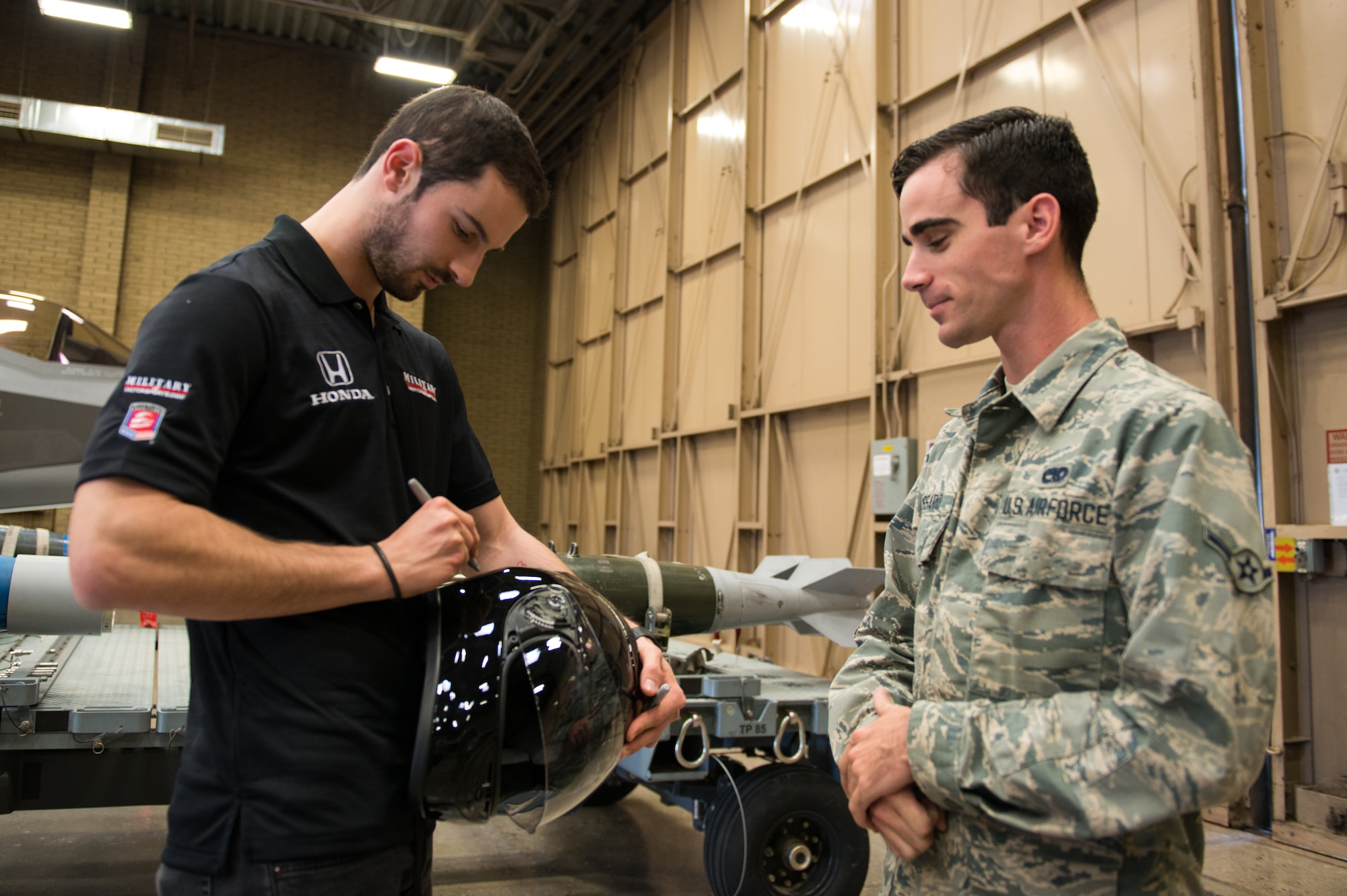 Alexander Rossi, Andretti Autosport team race car driver, autographs a helmet during his visit to Luke Air Force Base, Ariz., April 5, 2018. The Andretti Autosport team visited various units around base to gain insight on the mission of Luke and its Airmen. (U.S. Air Force photo by Airman 1st Class Alexander Cook)