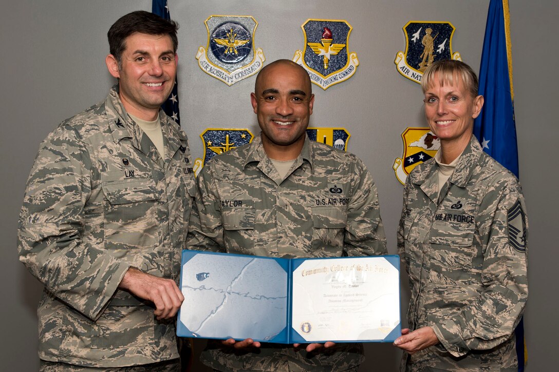 U.S. Air Force Reserve Tech Sgt. Vagus Taylor, aviation management, 96th Arial Port Squadron, poses for a photo with Col. Christopher Lay, the 913th Airlift Group commander, and Chief Master Sgt. Kimberly Lord, superintendent, 913th AG, after an All Call, April 7, 2018, at Little Rock Air Force Base, Ark. Schmidle received an Associate in Applied Science Aviation Management degree from the Community College of the Air Force. (U.S. Air Force photo by Master Sgt. Jeff Walston)