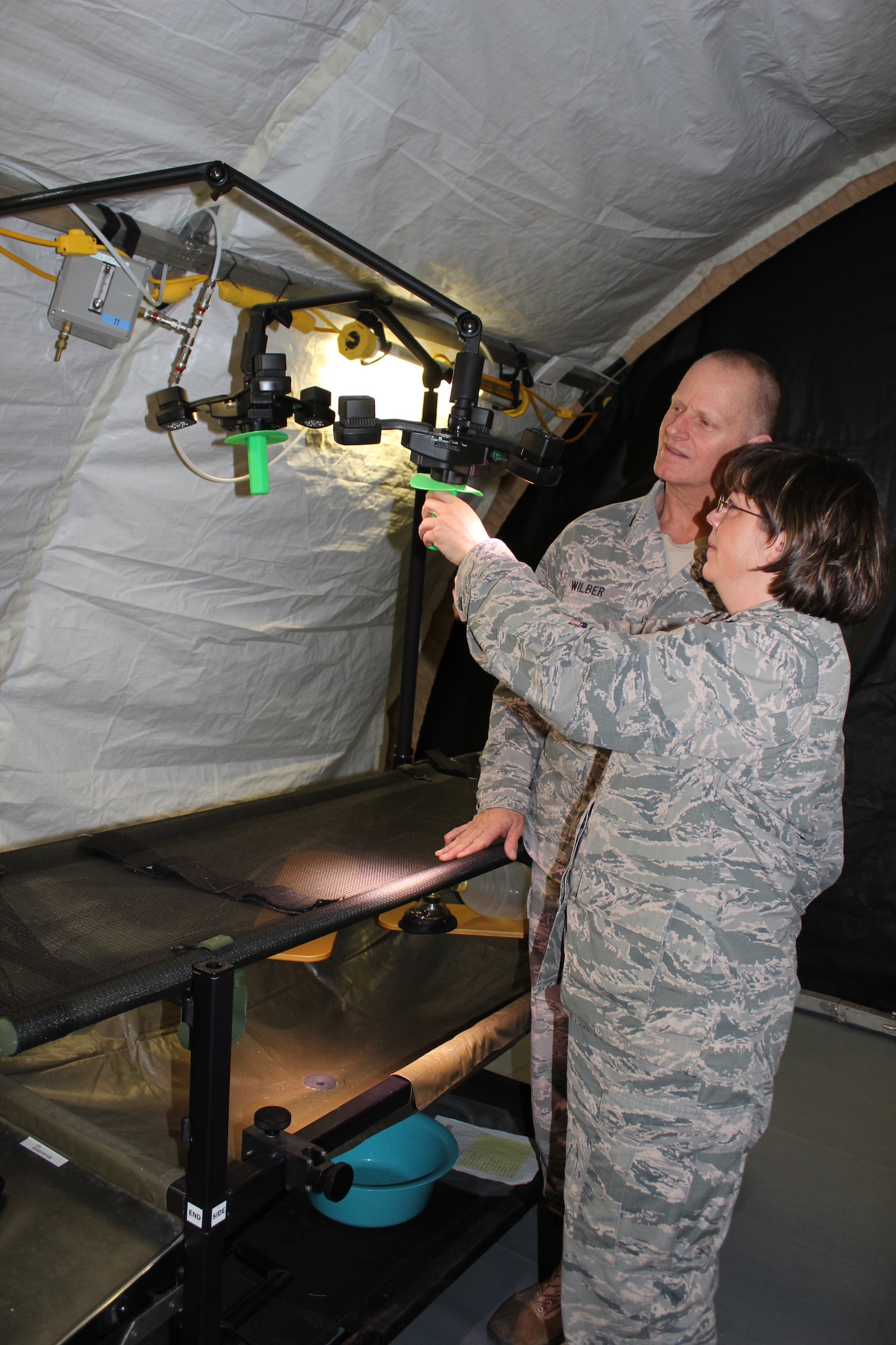 Lt. Col. Brandi Ritter and Lt. Col. Lewis Wilber, the Chief and Deputy Chief, Air Force Medical Evaluation Support Activity, examine the lights above a surgical table at the AMESA test facility at Ft. Detrick, Md. on Feb. 15, 2018. AFMESA investigated whether new, light-emitting diode (LED) lights could replace traditional surgical lights for use in deployed environments, but found that under the LEDs, surgeons could not determine if a patient’s flesh was necrotic. (U.S. Air Force photo by Shireen Bedi)