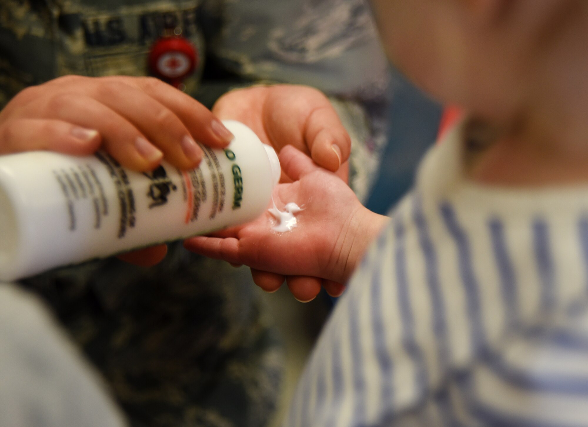 Airman Breanna Betti, 22nd Aerospace Medicine Squadron public health technician, gives a child lotion-based simulated germs during hand-washing training April 3, 2018, at the Child Development Center in McConnell Air Force Base, Kansas. Under a black light, the lotion lit up simulating the presence of germs. The toddlers then learned how to properly wash their hands and get all of the “germs” off.