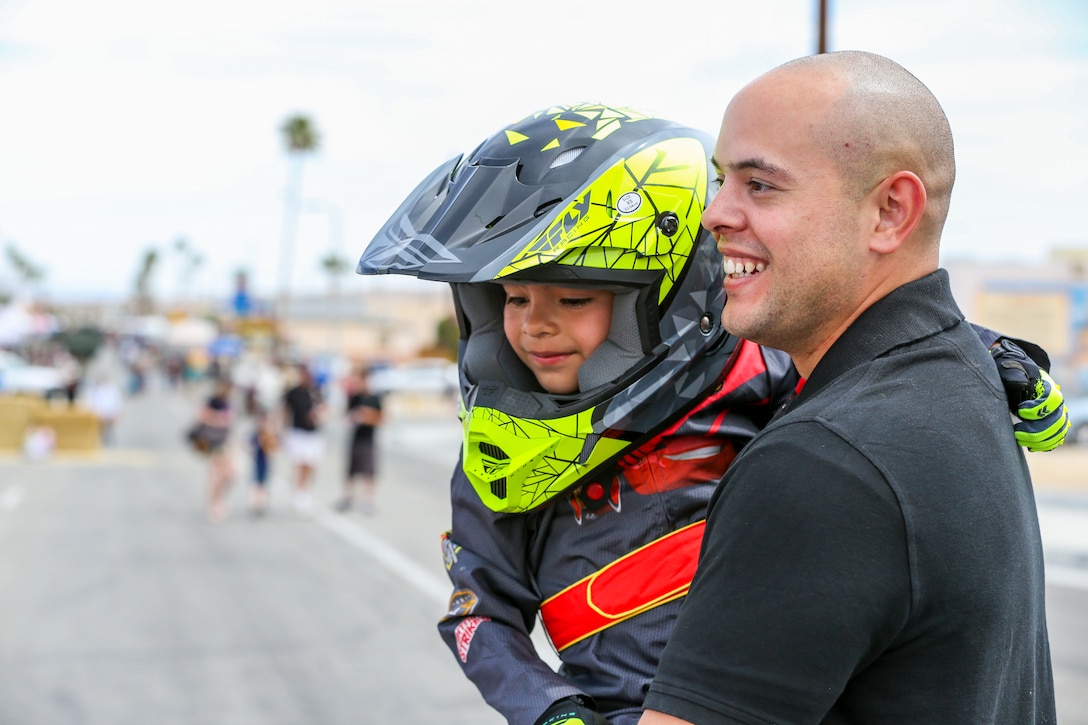 Gunnery Sgt. Joel A. Nieves, data chief, Tactical Training Exercise Control Group, holds his son, Nathaniel Nieves, 5, after his participation in the soapbox derby during the 18th Annual Car Show and Street Fair, which was hosted by the Twentynine Palms Chamber of Commerce in Twentynine Palms, Calif., March 31, 2018. The annual event is used to bring the community of Twentynine Palms and the Marine Corps Air Ground Combat Center, located in Twentynine Palms, together as well as support local businesses. (U.S. Marine Corps photo by Lance Cpl. Rachel K. Porter)