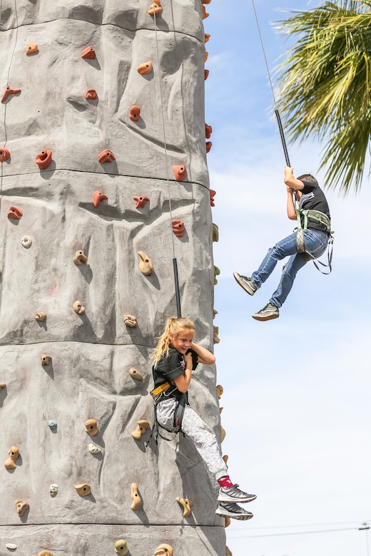 Kylie Hluk, 9, granddaughter of Jeff Hluk, Twentynine Palms patron, and Daniel Garcia, 8, nephew of Ramiro Garcia, Twentynine Palms patron, rappel from the Hand To Hand Marital Arts rock climbing tower during the 18th Annual Car Show and Street Fair, which was hosted by the Twentynine Palms Chamber of Commerce in Twentynine Palms, Calif., March 31, 2018. The annual event is used to bring the community of Twentynine Palms and the Marine Corps Air Ground Combat Center, located in Twentynine Palms, together as well as support local businesses. (U.S. Marine Corps photo by Lance Cpl. Rachel K. Porter)