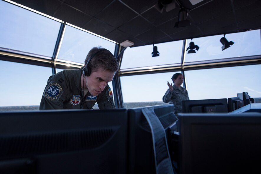 U.S. Air Force Capt. Kyle Rasmussen, 55th Fighter Squadron pilot acting as the air traffic control tower flying supervisor, records information on a computer while Staff Sgt. Elizabeth Gordon, 20th Operations Support Squadron watch supervisor, speaks with tower Airmen at Shaw Air Force Base, S.C., April 5, 2018.