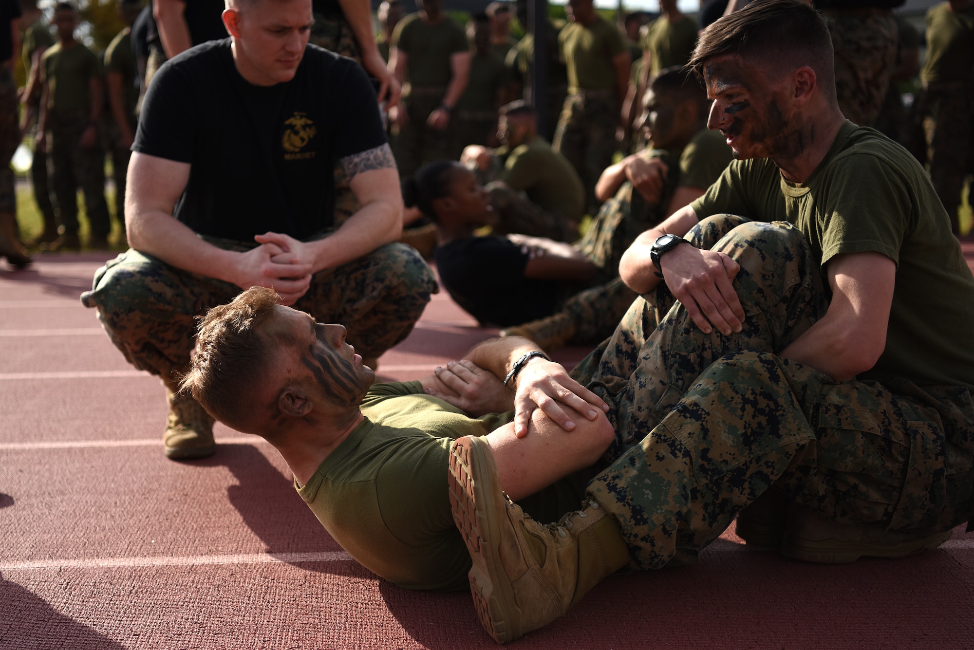 Keesler Marine Detachment students do crunches for the hip race at the Triangle Track during the 2nd Annual Warrior Day at Keesler Air Force Base, Mississippi, April 6, 2018. The hip race included 50 ammo can lifts, 20 burpees, 50 squats, 50 crunches and five squad pushups. The event served to promote unit cohesion, camaraderie and small unit leadership. (U.S. Air Force photo by Airman 1st Class Suzie Plotnikov)