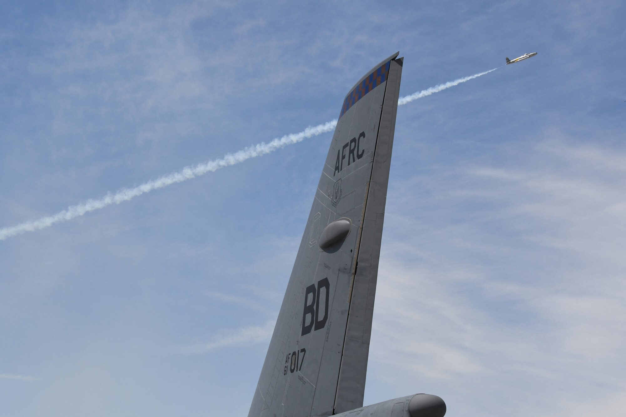 An aerial performer soars past the tail of a B-52 Stratofortress, assigned to the 307th Bomb Wing, during the March Field 2018 Air and Space Expo April 8, 2018.