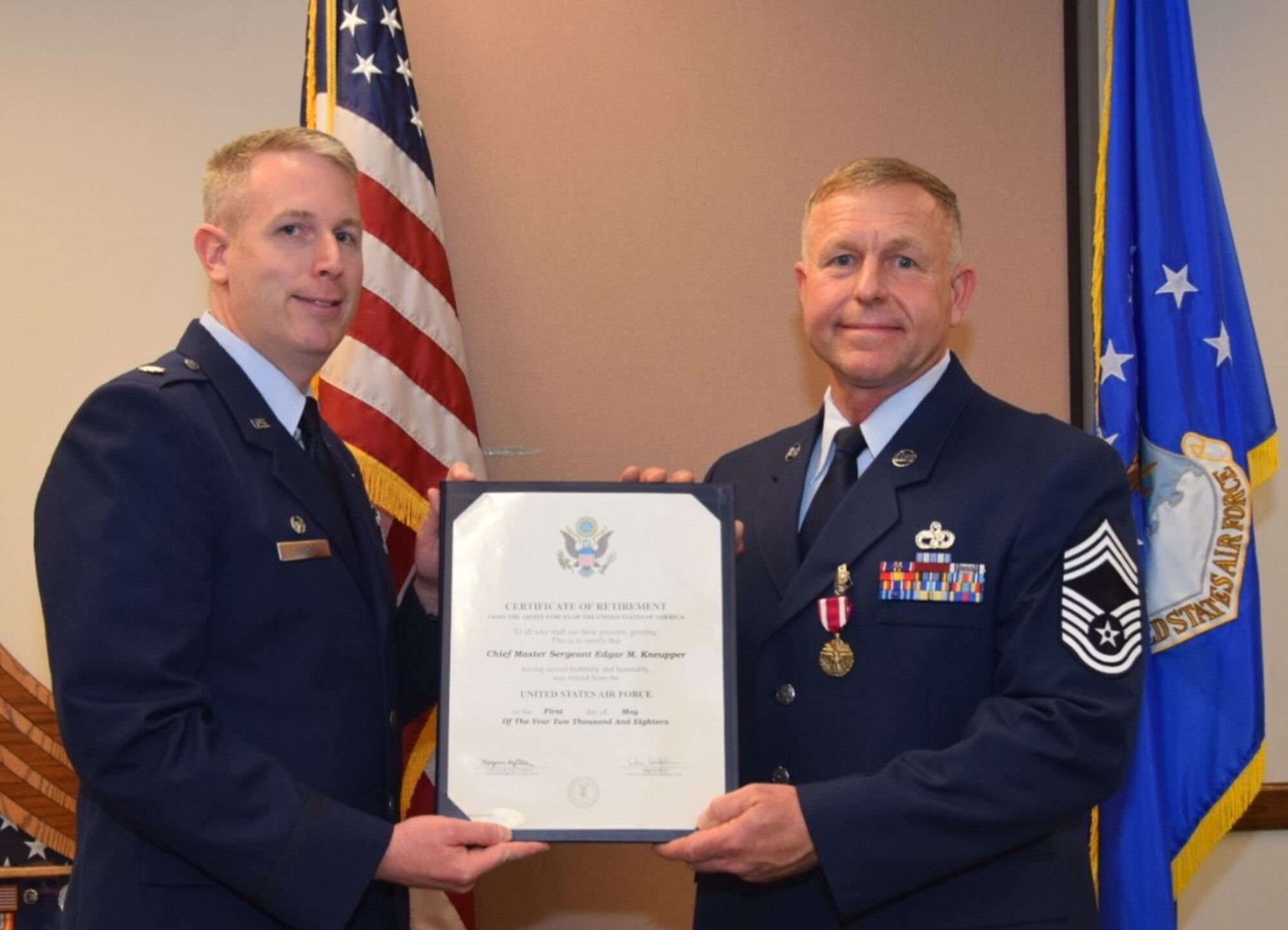 Lt. Col. Travis Hartley, 74th Aerial Port Squadron commander, presents a retirement certificate to Chief Master Sgt. Edgar M. Kneupper, 74th APS operations superintendent, April, 7 2018 on Joint Base San Antonio-Lackland, Texas. Kneupper initially enlisted in the Navy in 1985 before transitioning to the Air Force in 1995. (U.S. Air Force photo by Tech Sgt. Carlos J. Treviño)