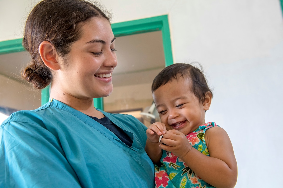 A sailor holds a giggling girl.