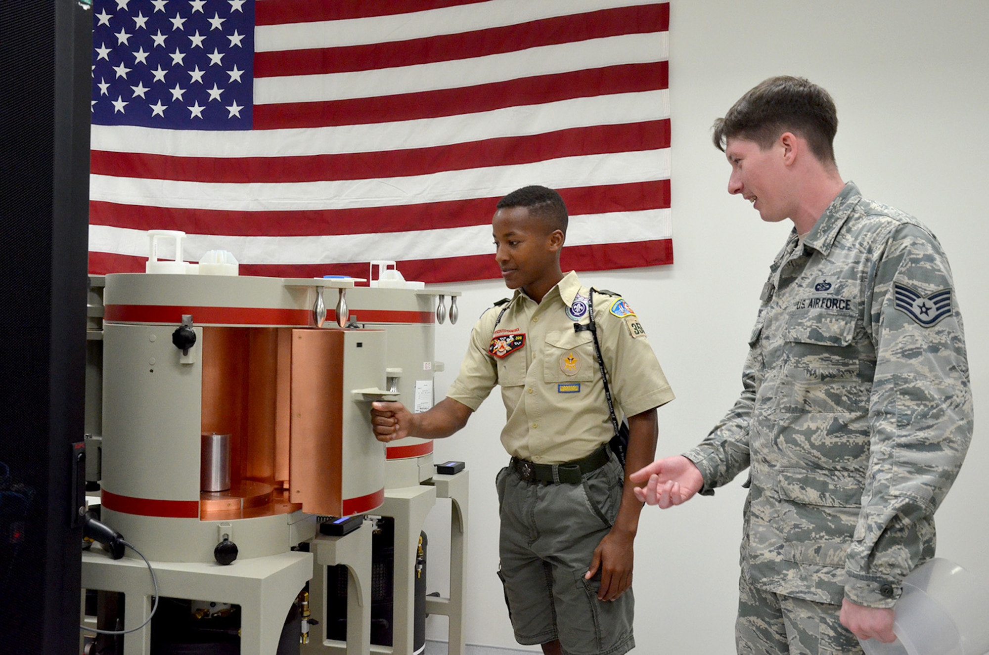 Larry Edgecombe, an 8th grader at Holy Trinity Episcopal Academy and member of Boy Scout Troop #355, opens the door of a gamma ray detector as Staff Sgt. Nicholas Jarvis, a radiochemistry lab technician, observes and explains how the detector works.  Edgecombe was one of 98 scouts who visited the Air Force Technical Applications Center March 31, 2018 to earn the Nuclear Science Merit Badge with the help of AFTAC Airmen.  (U.S. Air Force photo by Susan A. Romano)