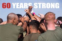 Marines with 3rd Marine Logistics Group huddle together to cheer on their flag football team during 3rd MLG’s 60th Anniversary celebration April 10, 2018 on Camp Hansen, Okinawa, Japan. 3rd MLG Marines and Sailors conquered numerous challenges and competed in various team competitions such as sports, fire team and squad competitions, and tug-of-war, and took part in family events and a cake-cutting ceremony. The anniversary celebration built camaraderie between the service members and families. (U.S. Marine Corps photo by Pfc. Hannah Hall)