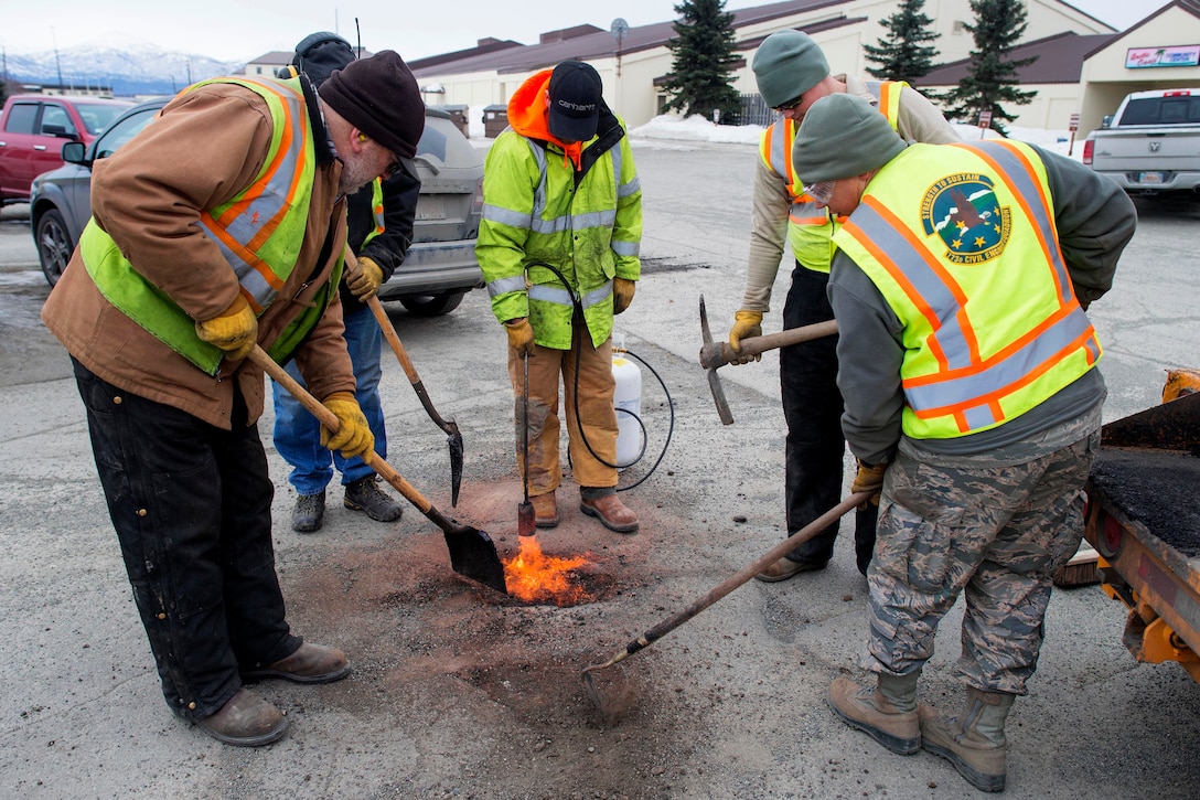 Airmen and civilian personnel repair potholes.