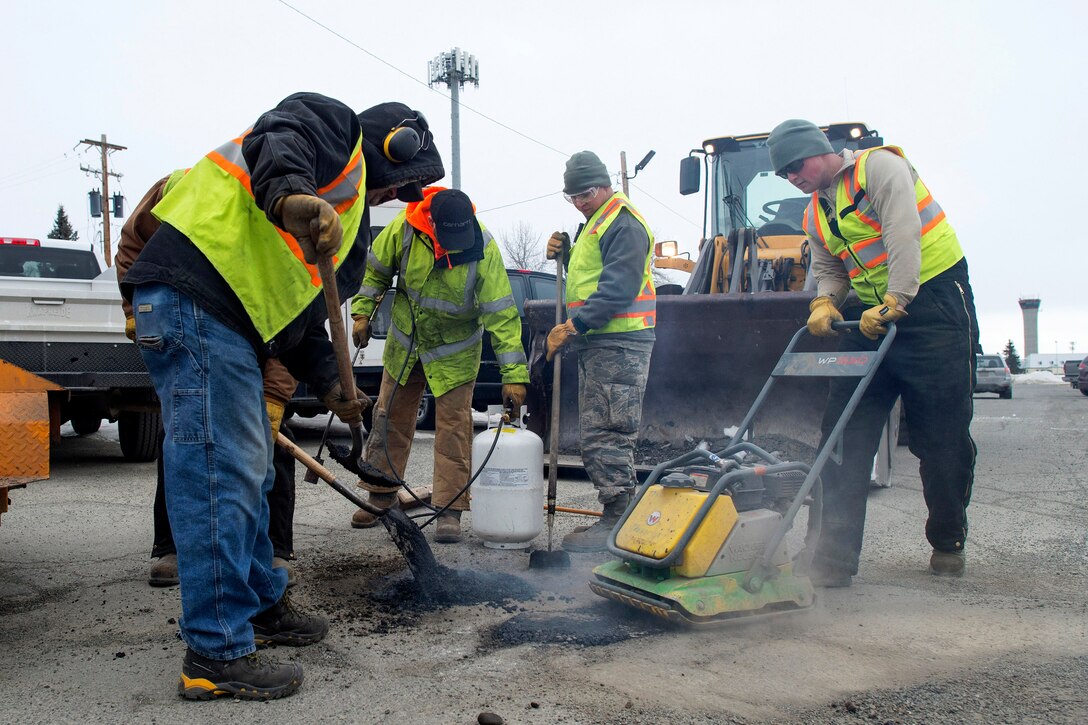 Airmen and civilian personnel repair potholes.
