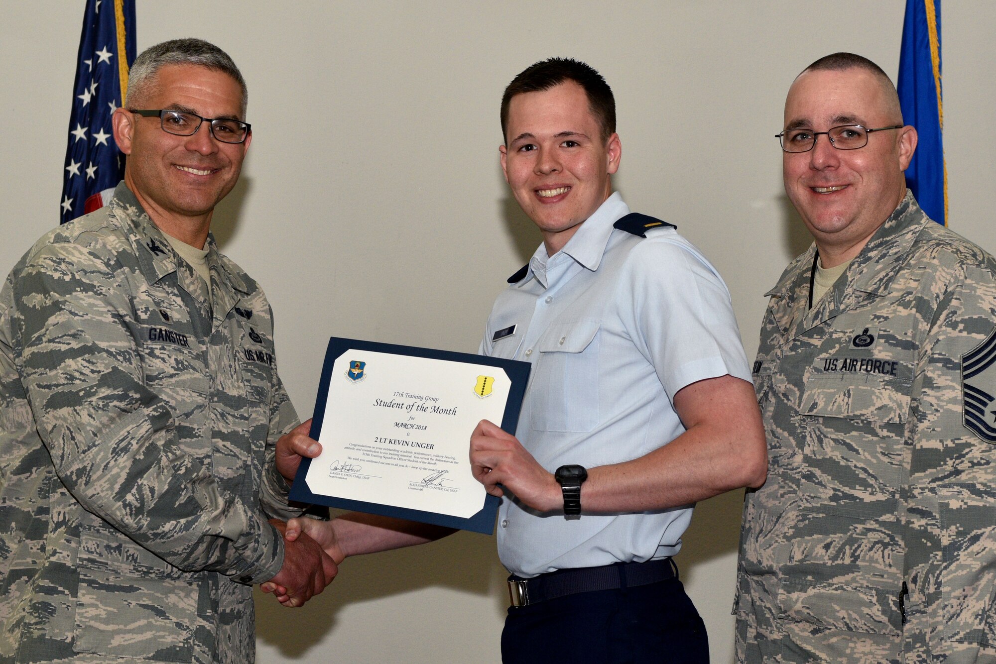 U.S. Air Force Col. Alex Ganster, 17th Training Group commander, and Chief Master Sgt. Daniel Stein, 17th TRG superintendent, present the 315th Training Squadron Officer Student of the Month certificate to 2nd Lt. Kevin Unger, 315th TRS trainee, in the Event Center on Goodfellow Air Force Base, Texas, April 6, 2018. The 315th TRS’s vision is to develop combat-ready intelligence, surveillance and reconnaissance professionals and promote an innovative squadron culture and identity unmatched across the U.S. Air Force. (U.S. Air Force photo by Senior Airman Randall Moose/Released)