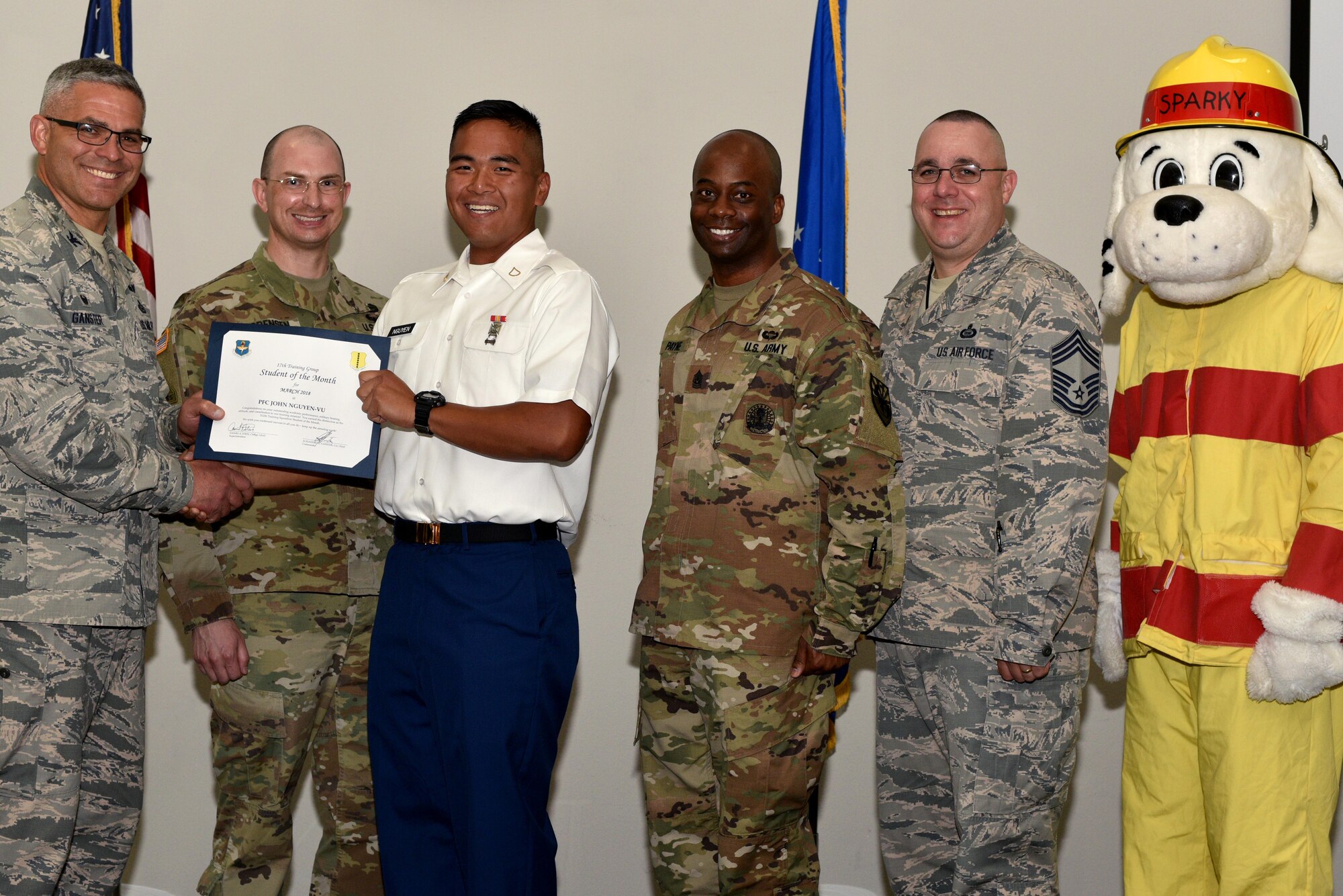 U.S. Air Force Col. Alex Ganster, 17th Training Group commander, and Chief Master Sgt. Daniel Stein, 17th TRG superintendent, present the 312th Training Squadron Student of the Month certificate to U.S. Army Private 1st Class John Nguyen-Vu, 312th TRS trainee, in the Event Center on Goodfellow Air Force Base, Texas, April 6, 2018.  The 312th TRS’s mission is to provide Department of Defense and international customers with mission ready fire protection and special instruments graduates and provide mission support for the Air Force Technical Applications Center. (U.S. Air Force photo by Senior Airman Randall Moose/Released)