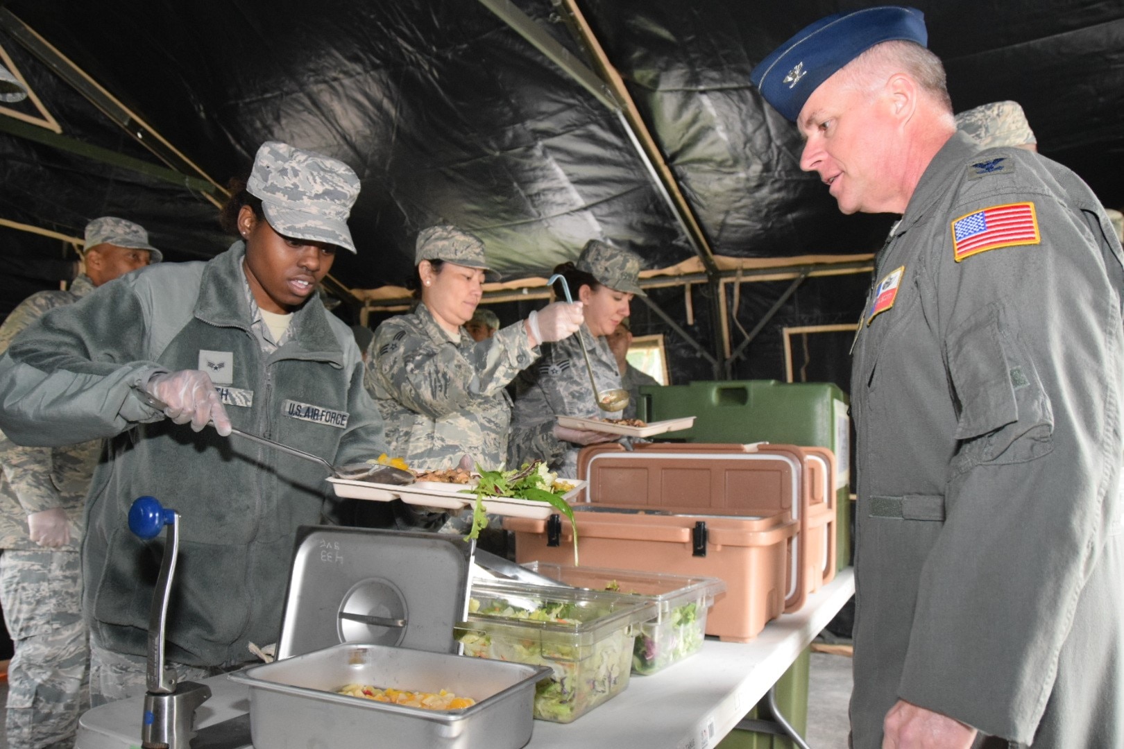 Senior Airman Chelsea Smith, 433rd Force Support Squadron food services specialist, serves lunch to Col. David Scott, 433rd Airlift Wing vice commander, from a Single Pallet Expeditionary Kitchen April 7, 2018. The sustainment flight served a lunch that consisted of southwestern chicken, white rice, garden salad, fruit cocktail and red velvet cake to Alamo Wing leadership. (U.S. Air Force photo by Tech Sgt. Carlos J. Treviño)