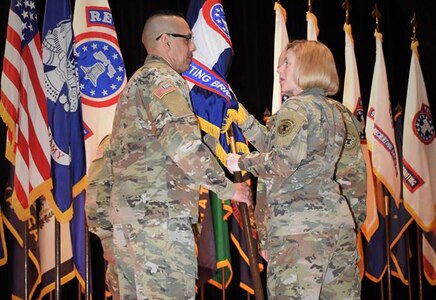 Two Soldiers pass a guide on flag to signify change of responsibility.