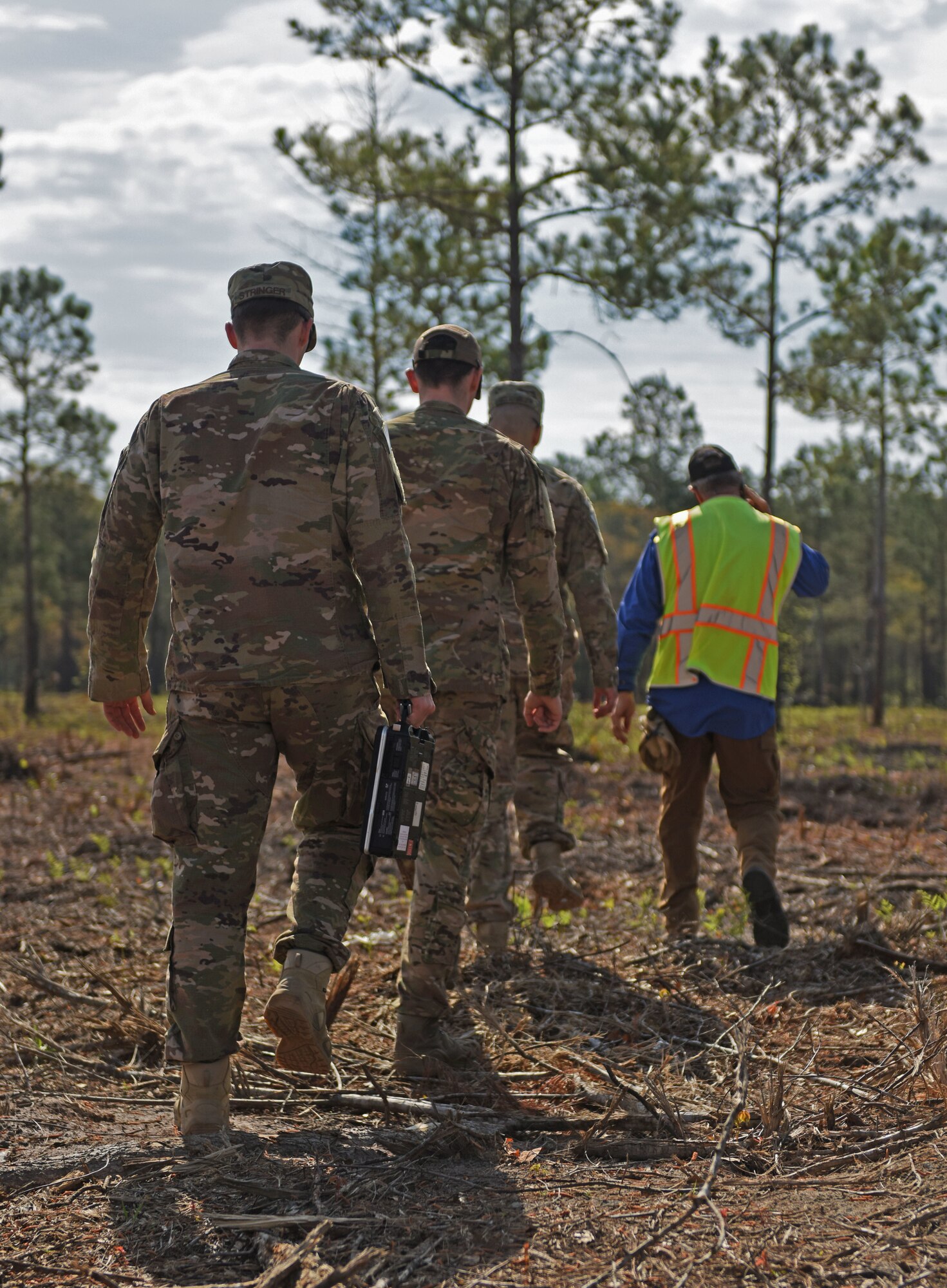 U.S. Airmen walk with a construction worker to a site where multiple unexploded ordinance lie in Conway, S.C., April 4, 2018.