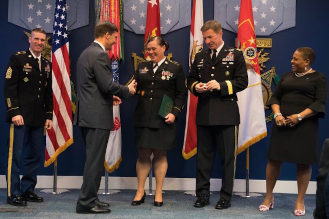 Army Secretary Mark Esper shakes hands and presents an award.