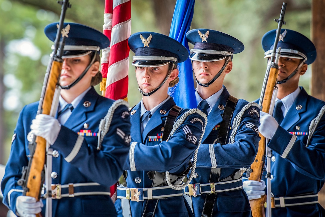 Four airmen carry flags and weapons.