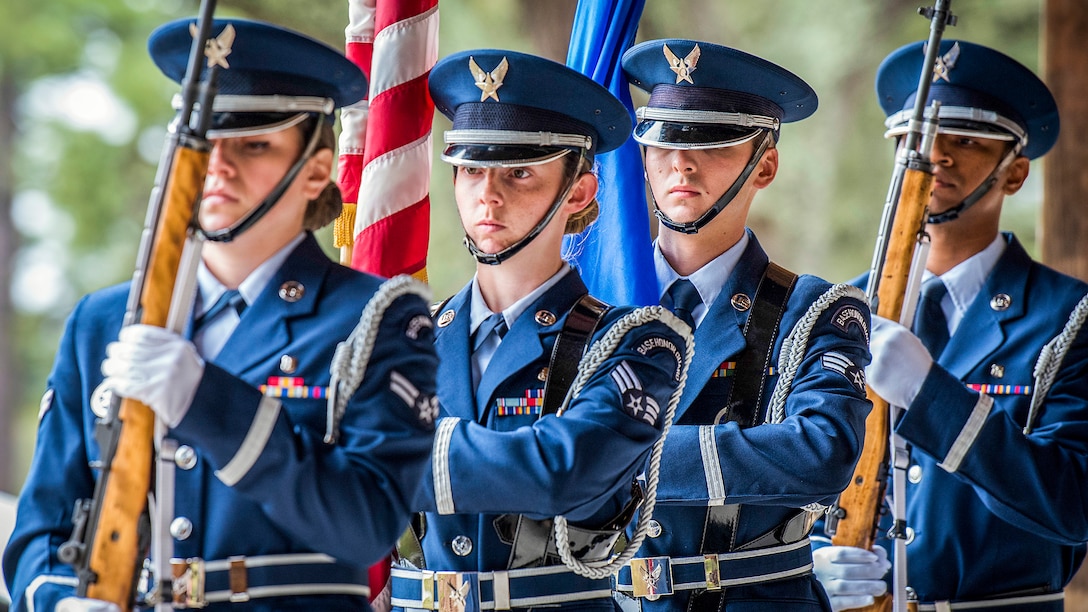 Four airmen carry flags and weapons.