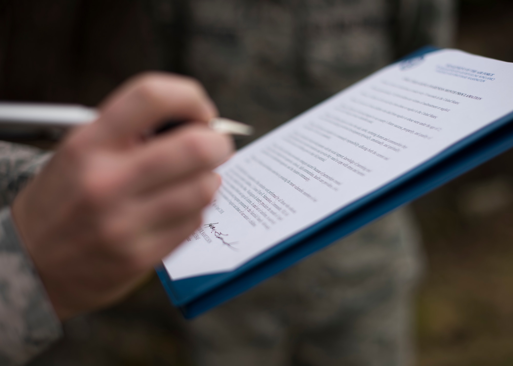 Col. Ryan Samuelson, 92nd Air Refueling Wing commander, signs a proclamation of intent at a base pinwheel ceremony in honor of Child Abuse Awareness Month at Fairchild Air Force Base, Washington, April 9, 2018. Airmen installed pinwheels at the base chapel to honor Child Abuse Awareness Month. (U.S. Air Force photo/Senior Airman Ryan Lackey)