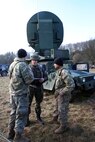 Soldiers talking in front of satellite dish