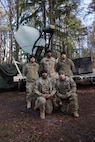 Soldiers posing in front of satellite dish
