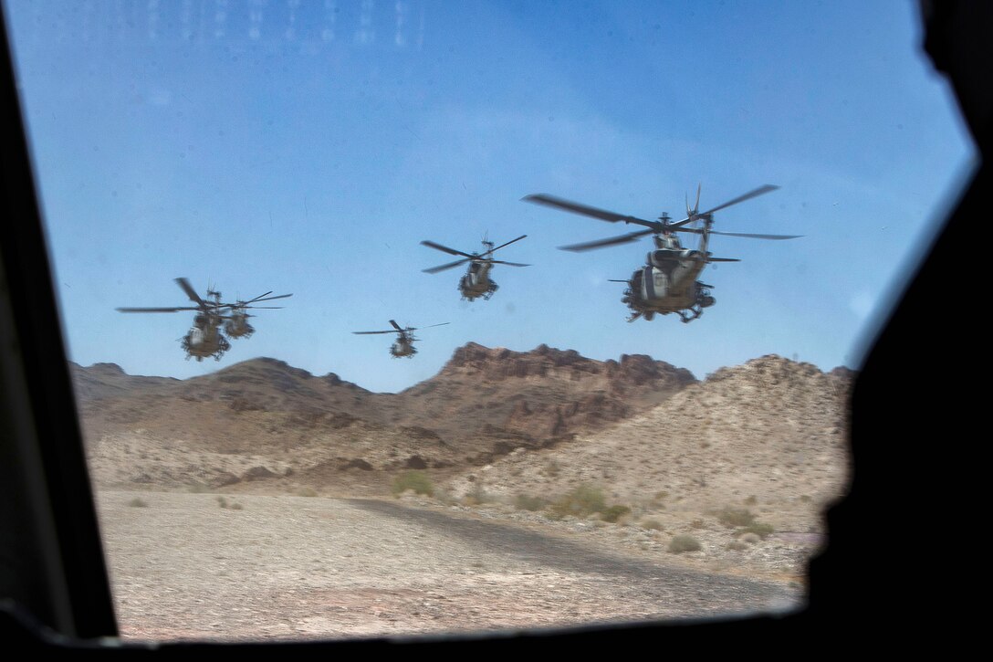 Five Marine Corps helicopters fly in formation for an attack pass.