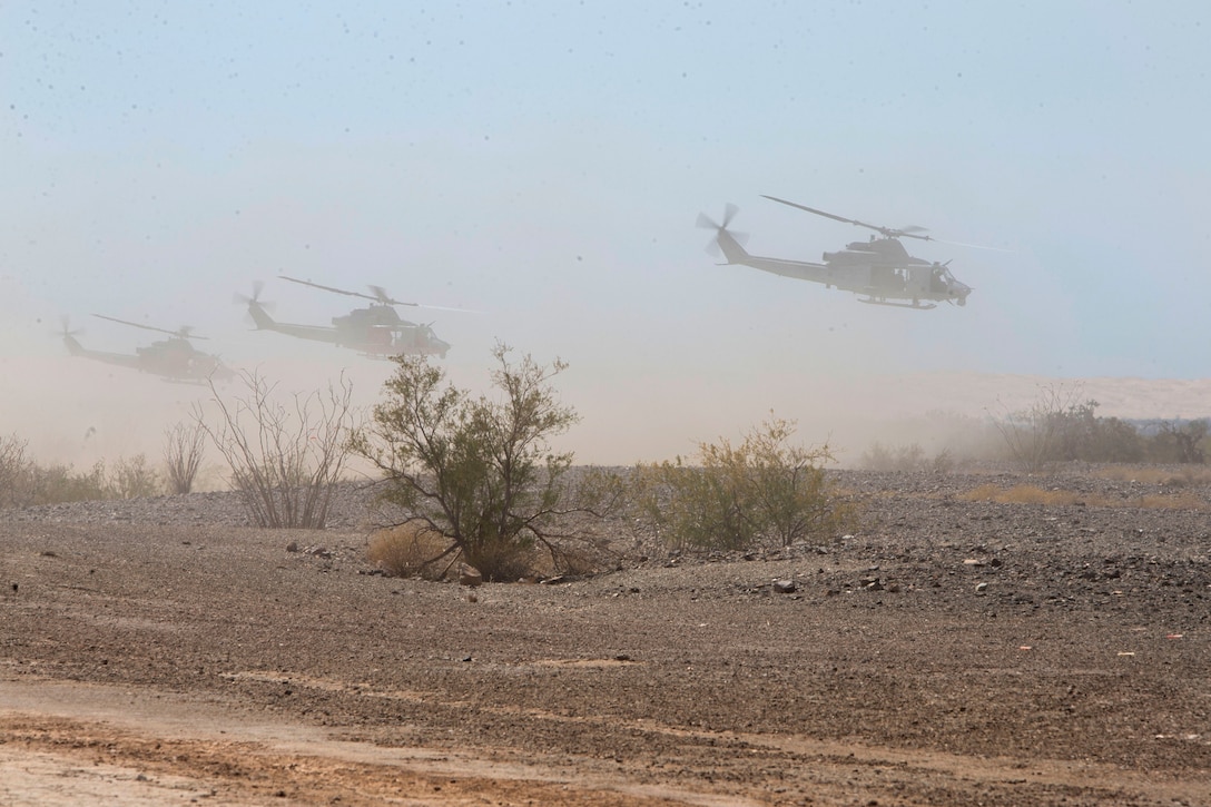 Three Marine Corps helicopters takeoff after being re-armed.