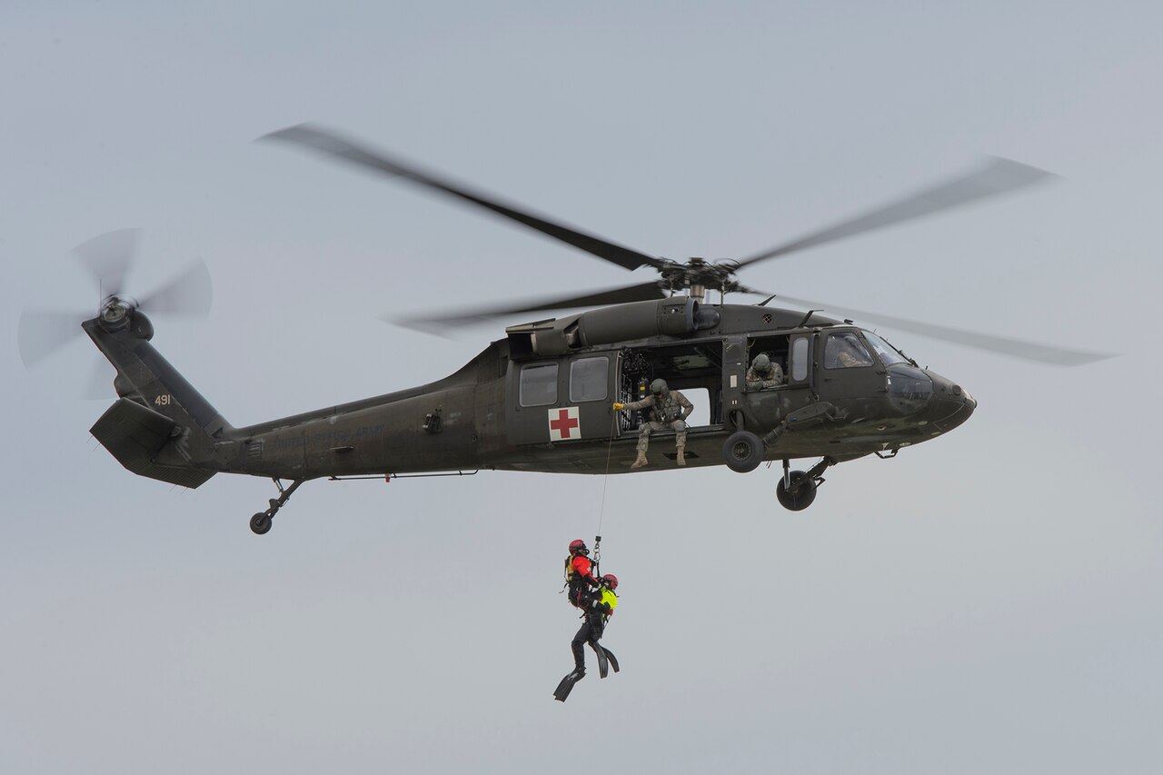 Diver ropes down to water from helicopter.