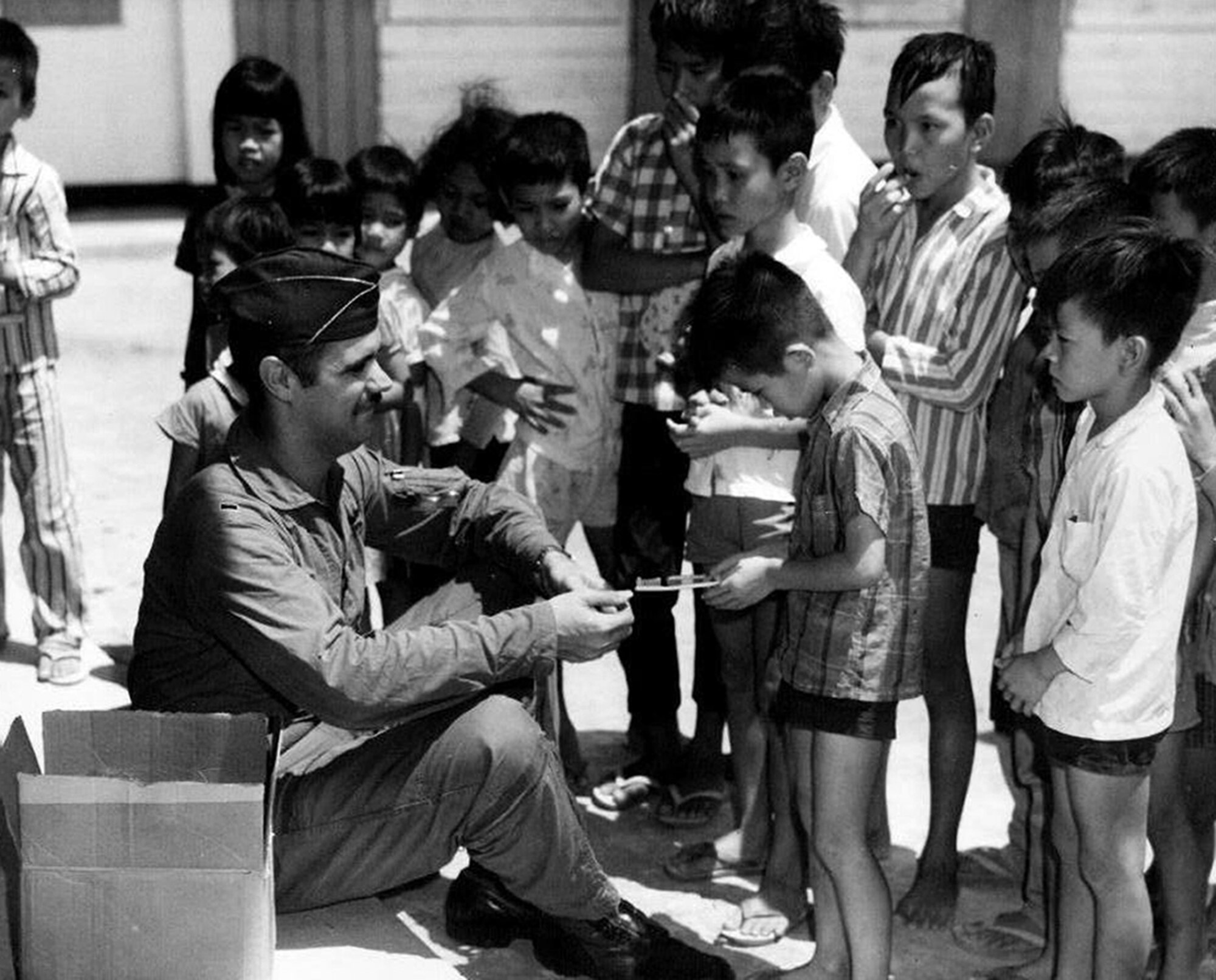 While stationed at Bien Hoa Air Base, Vietnam, then-1st Lt. Fred Abrams, an Air Force F-100 “Super Sabre” fighter pilot, distributes items to children as part of a humanitarian initiative. Despite the combat actions taking place around them, it wasn’t always flying fighter missions for Abrams and his squadron, 531st Tactical Fighter Squadron, which supported a school, an orphanage and a leper colony. The now-retired Abrams feels that these helping efforts which military members often make during wartime should be remembered. For him, those non-combat experiences away from the cockpit helped shape his future desires to provide service to others.