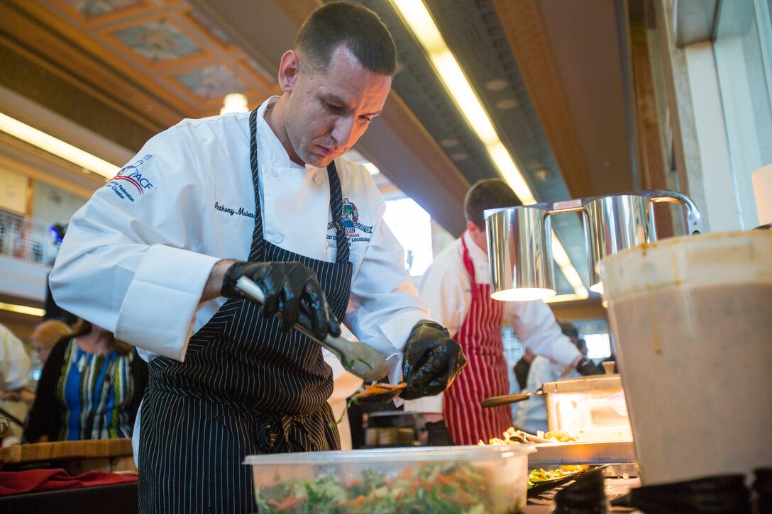 Staff Sgt. Anthony Maietta (right), an enlisted aide to Lt. Gen. Rex C. McMillian, commander of Marine Forces Reserve and Marine Forces North prepares his dish before placing them for attendees to try at the annual Best Chef Louisiana competition at the Lakefront Airport Terminal Building, New Orleans, April 10, 2018. The chefs event gives recognition to select chefs and honors them for their contribution to the New Orleans culinary scene and is also an opportunity for them to showcase their talent by serving a sampling of their signature dishes to the attendees.