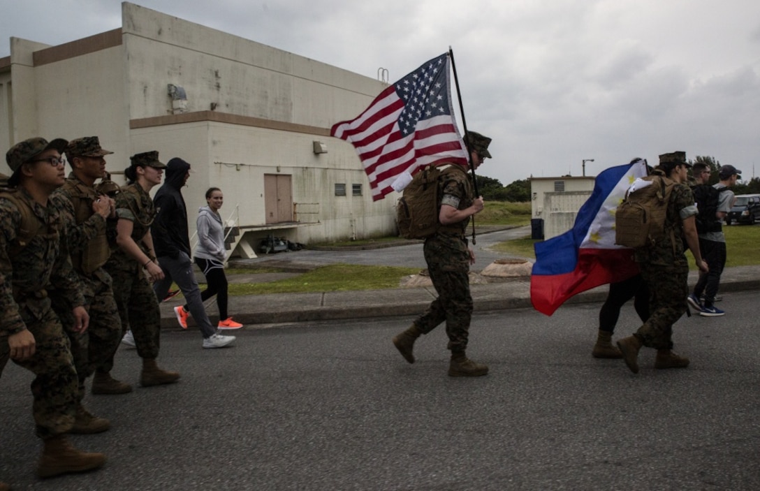 A Marine with 1st Marine Aircraft Wing carries the American Flag during the Bataan Death March Memorial hike, April 7, 2018 on Kadena Air Force base, Okinawa, Japan.
 More than 200 service members and their families participated in the 8.5 mile hike around Kadena’s perimeter in remembrance of the prisoners of war who perished as a result of the Death March that took place in the Philippine archipelago in 1942 during WWII. (U.S. Marine Corps photo by Sgt. Natalie Dillon)