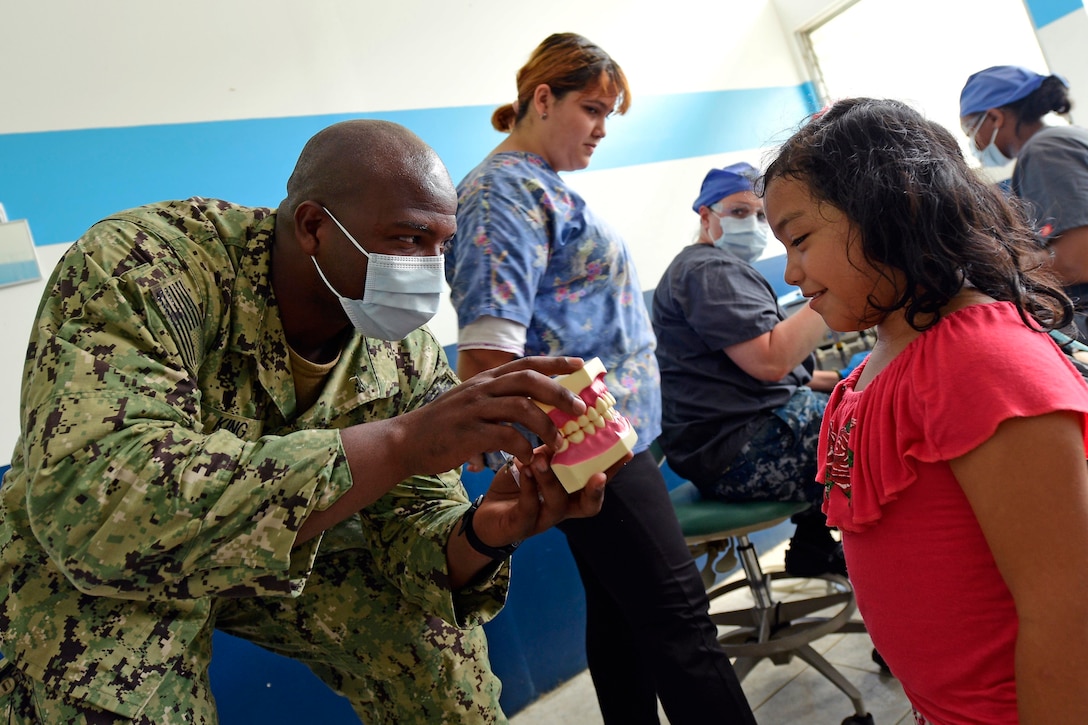 A military doctor hows a Guatemalan girl model teeth.