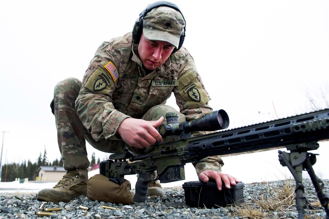 A soldier adjusts the scope on a sniper rifle.