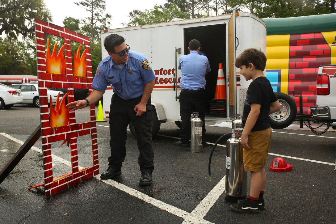 A firefighter demonstrates fire safety to a local child during Kids Fest in downtown Beaufort, April 7. April is Month of the Military Child and Child Abuse Prevention Month. The firefighter is with Beaufort County Fire and Rescue.