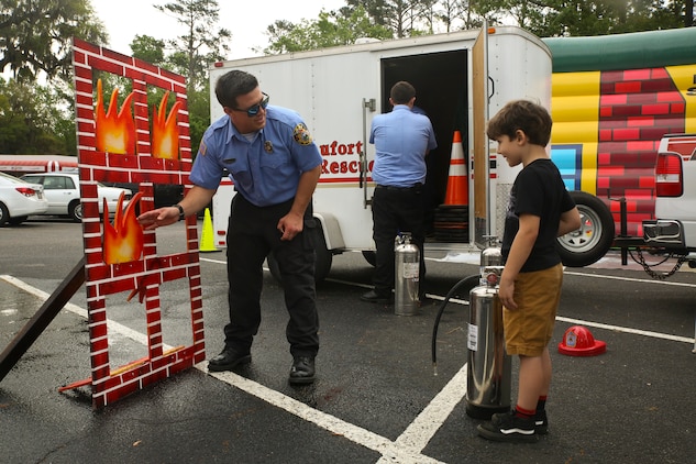 A firefighter demonstrates fire safety to a local child during Kids Fest in downtown Beaufort, April 7. April is Month of the Military Child and Child Abuse Prevention Month. The firefighter is with Beaufort County Fire and Rescue.
